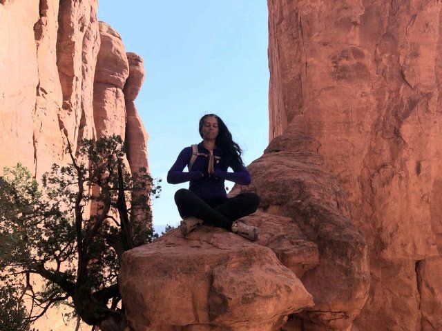 A person contemplating the landscape between red sandstone cliffs
